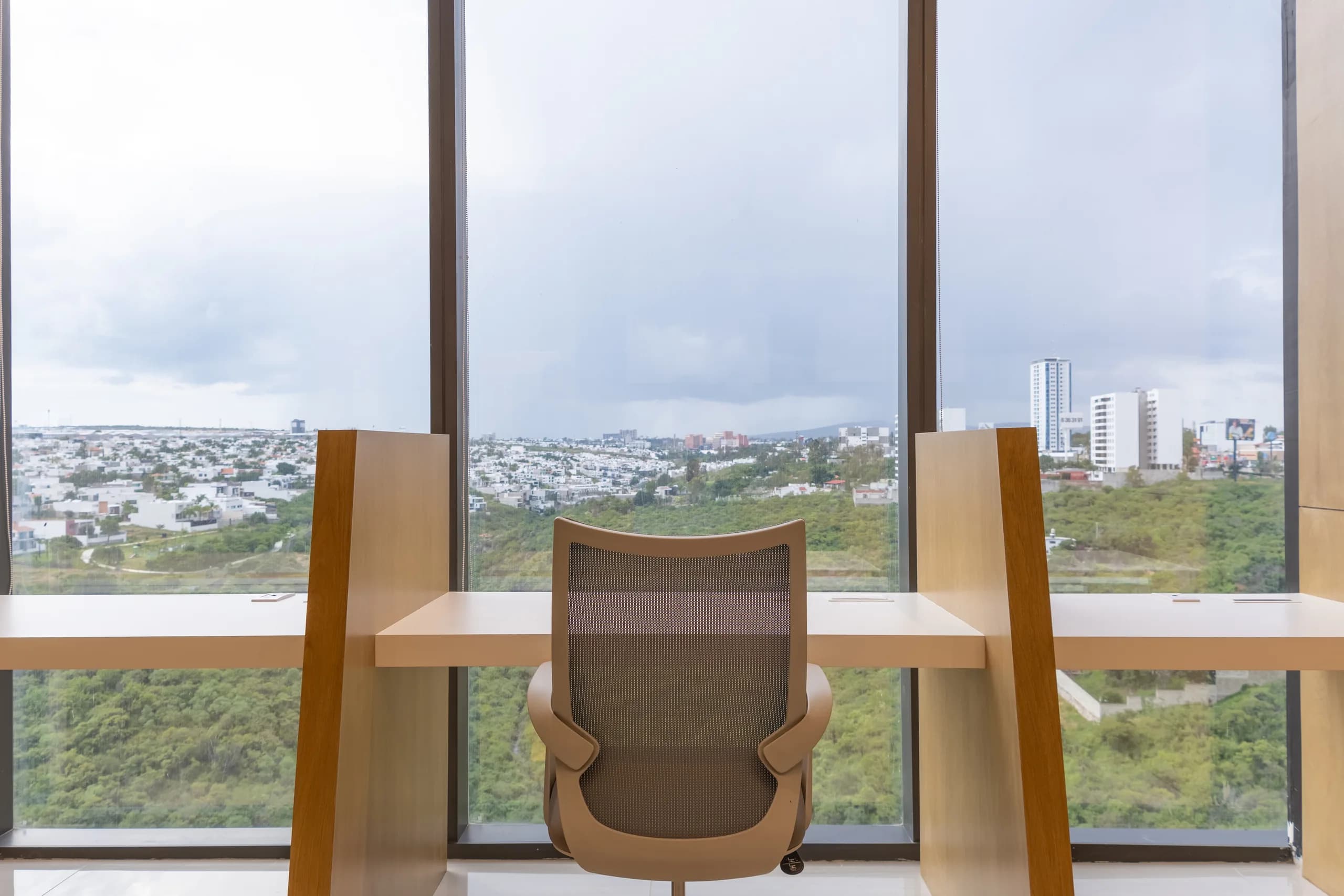 Escritorio de madera frente a un ventanal con vista a la ciudad
