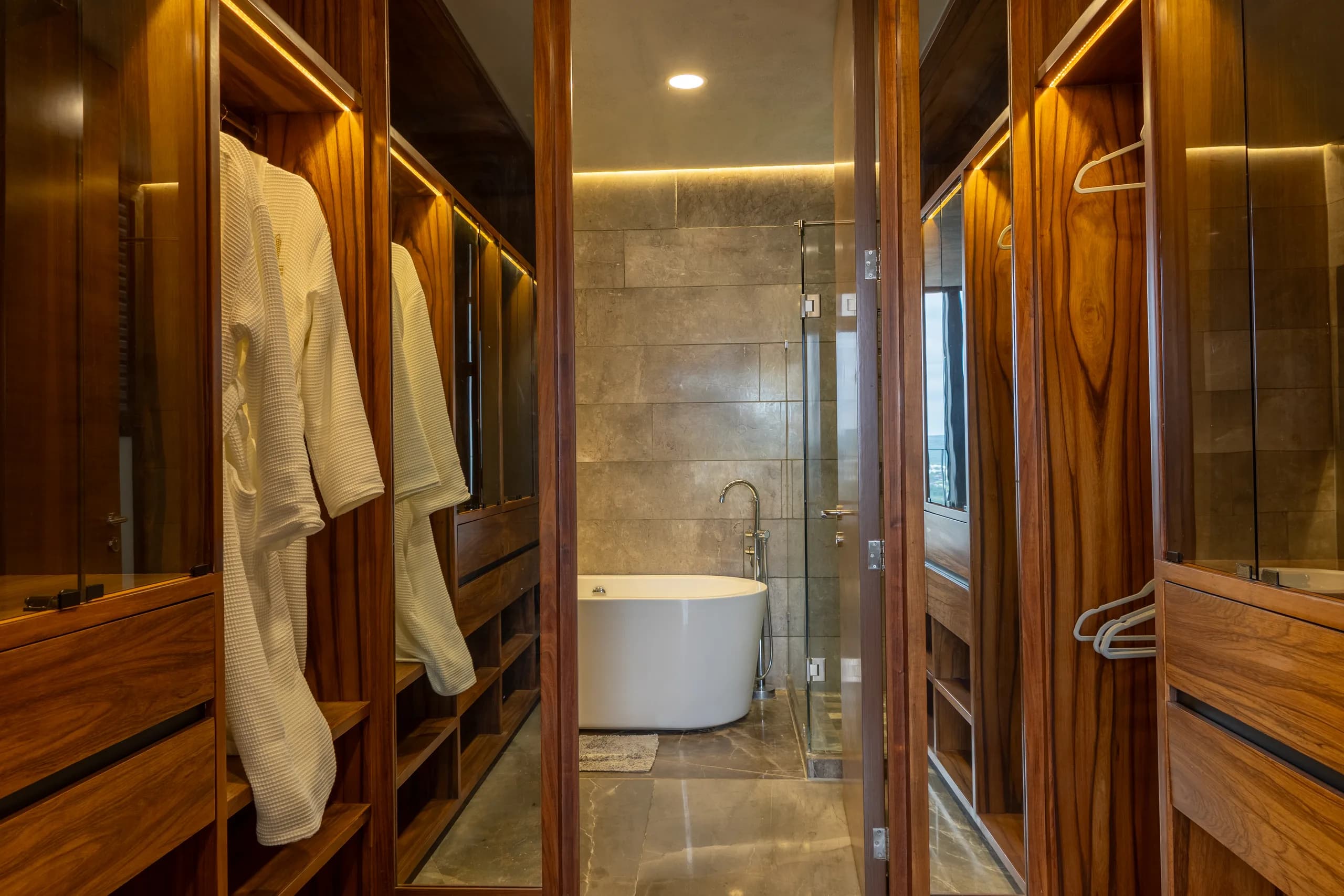 Vestidor de madera que da a un baño con tina exenta
